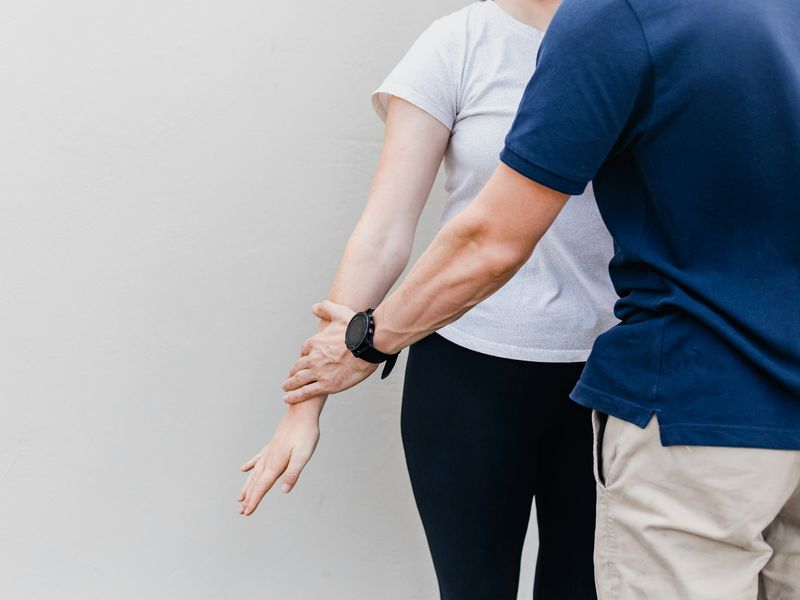 Hands guiding a patient's arm through a shoulder movement check