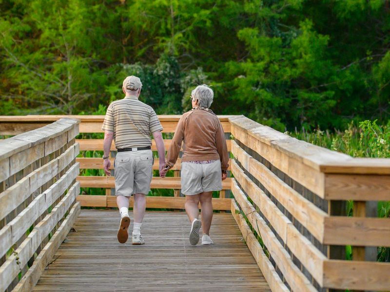 Older couple walking together on a wooden boardwalk