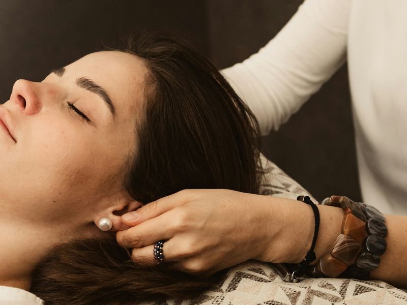 Patient resting while hands gently support her head and neck