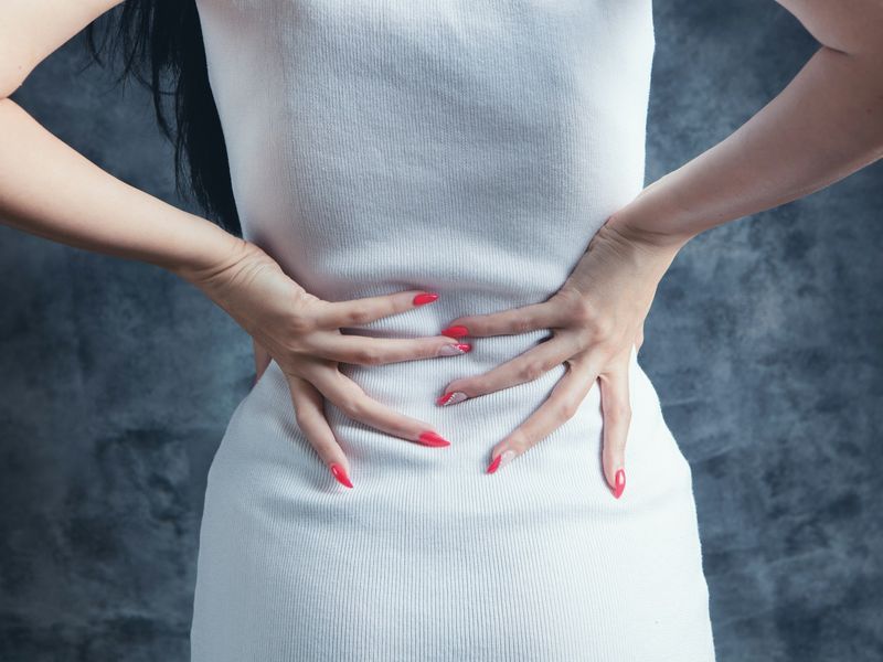Woman holding her lower back with both hands