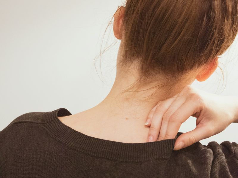Woman rubbing a sore spot at the base of her neck