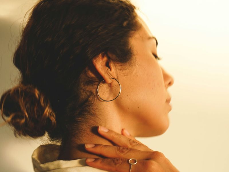 Woman holding the side of her neck